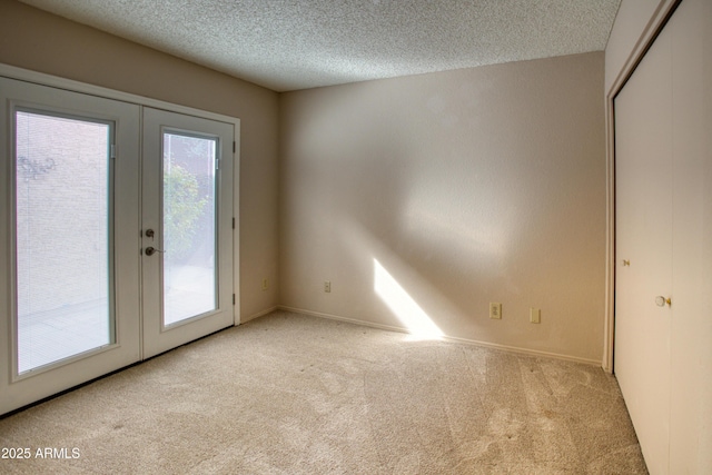 doorway with light carpet, a textured ceiling, and french doors