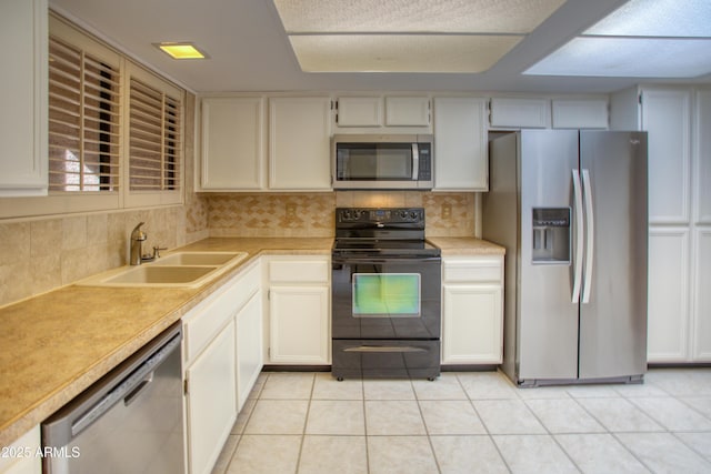 kitchen with white cabinetry, appliances with stainless steel finishes, sink, and light tile patterned floors