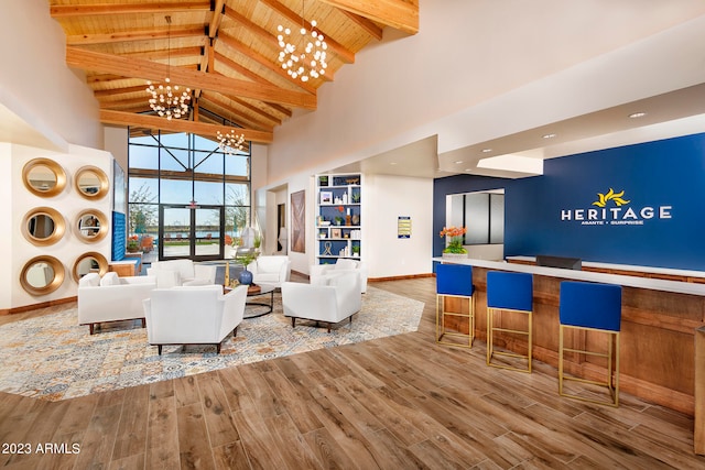 living room with hardwood / wood-style flooring, a notable chandelier, high vaulted ceiling, and beam ceiling