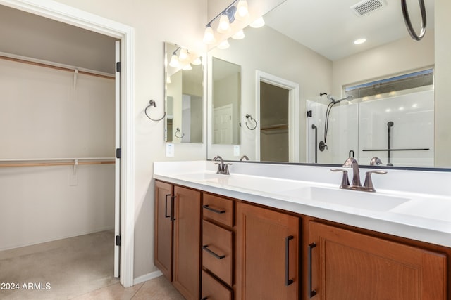 bathroom featuring tile patterned flooring, vanity, and a shower