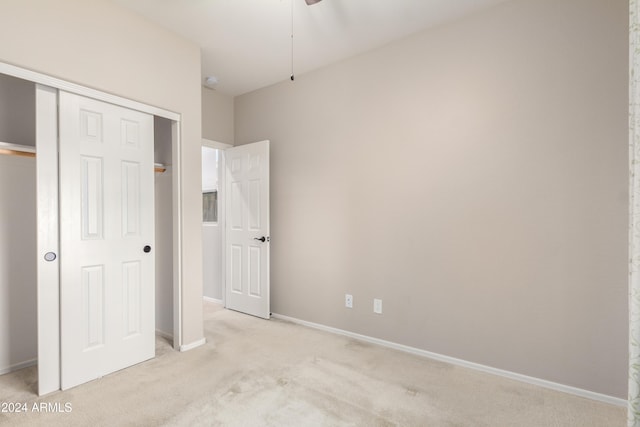 unfurnished bedroom featuring light colored carpet and a closet