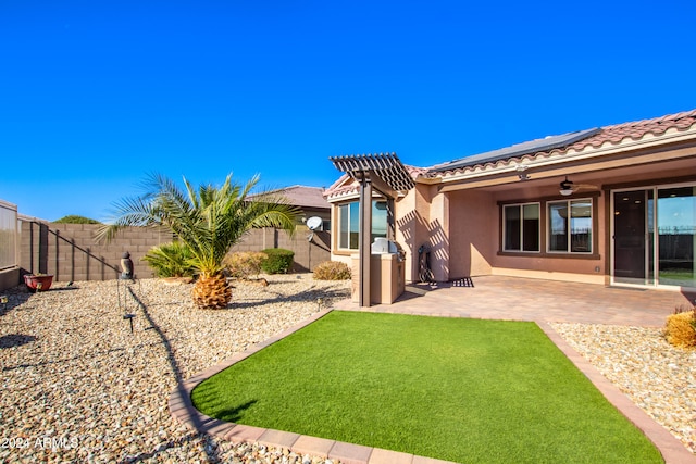 rear view of property with ceiling fan and a patio area