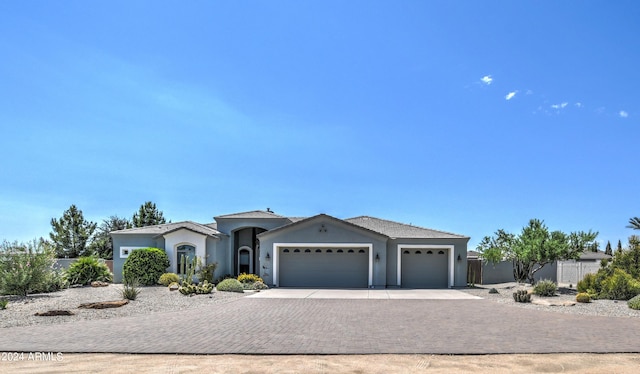 ranch-style house with a garage, decorative driveway, fence, and stucco siding