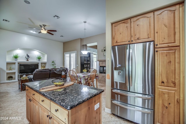 kitchen with a glass covered fireplace, dark stone counters, visible vents, and stainless steel fridge