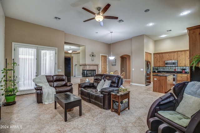 living area with a fireplace, arched walkways, visible vents, and a ceiling fan