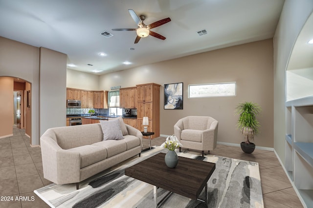 living room with visible vents, arched walkways, light tile patterned flooring, and a ceiling fan