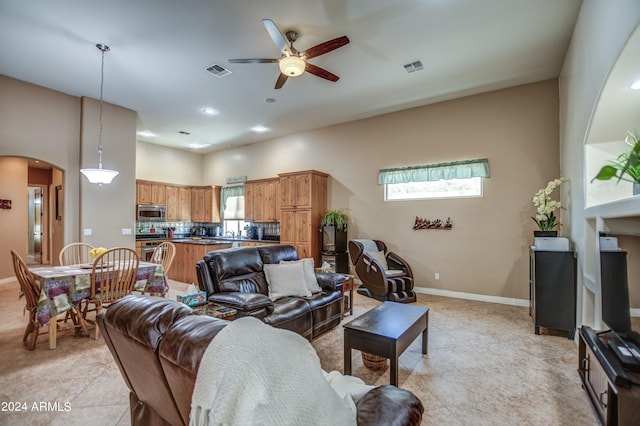 living area featuring arched walkways, visible vents, a ceiling fan, and baseboards