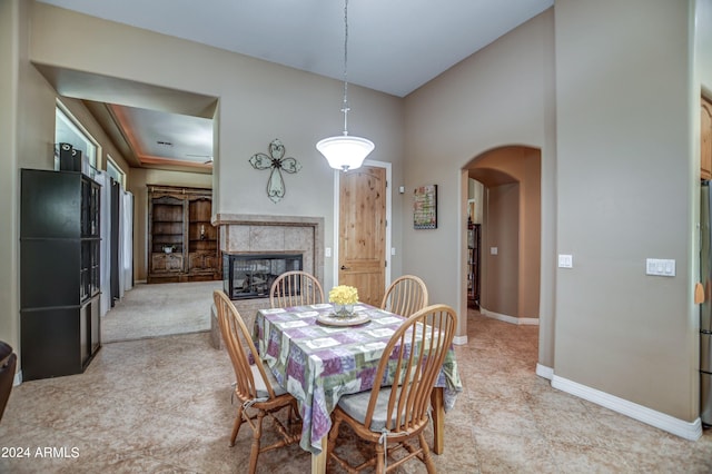 dining space featuring a high ceiling, baseboards, arched walkways, and a tile fireplace