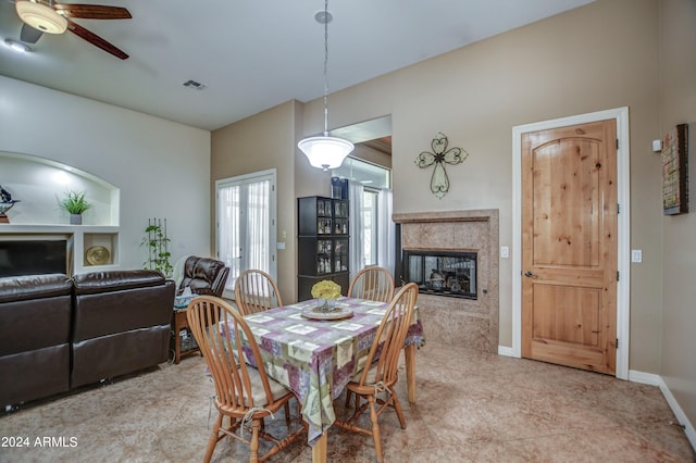 dining room featuring baseboards, a ceiling fan, visible vents, and a premium fireplace