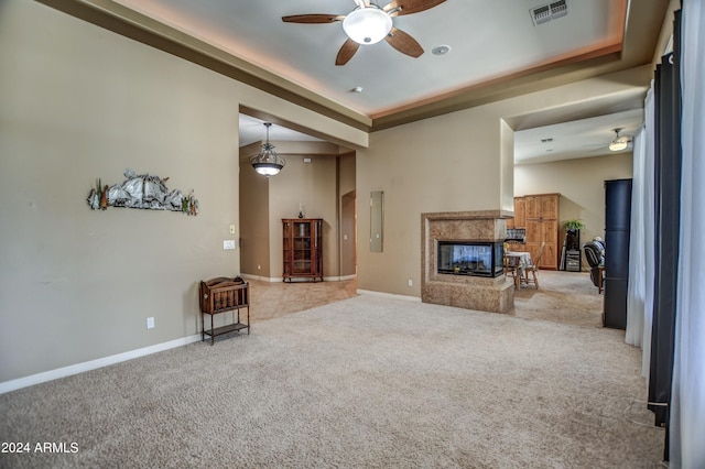 living room with carpet, visible vents, baseboards, a premium fireplace, and a tray ceiling