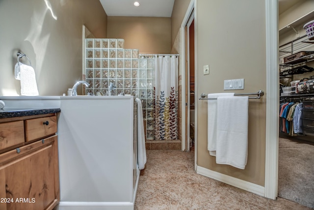 bathroom with vanity, a shower with shower curtain, a walk in closet, and baseboards