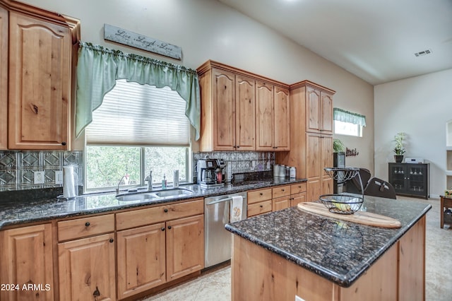 kitchen with visible vents, dark stone counters, a sink, stainless steel dishwasher, and backsplash