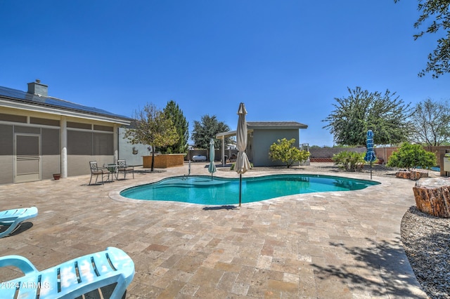 view of pool featuring a patio, a fenced in pool, a fenced backyard, a sunroom, and an outdoor structure