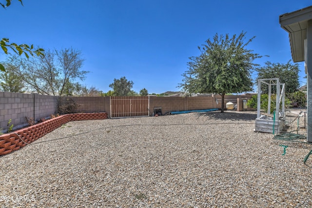 view of yard with a fenced backyard and a gate