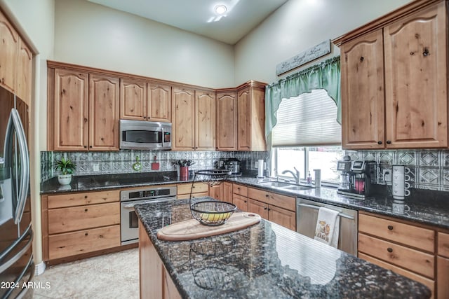 kitchen featuring a sink, decorative backsplash, appliances with stainless steel finishes, and dark stone countertops