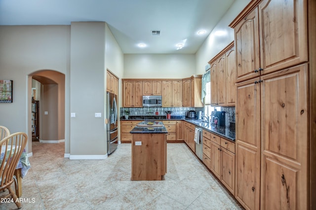 kitchen with visible vents, a center island, decorative backsplash, appliances with stainless steel finishes, and arched walkways