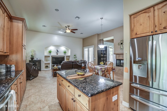 kitchen featuring dark stone countertops, open floor plan, a high end fireplace, a center island, and stainless steel fridge with ice dispenser