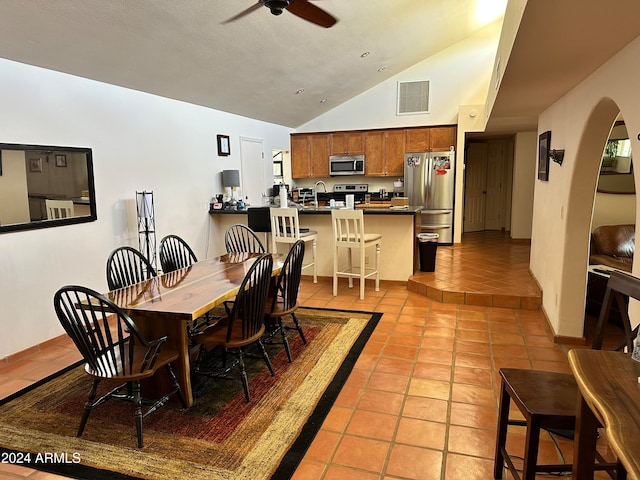 dining space with lofted ceiling, sink, light tile patterned flooring, and ceiling fan