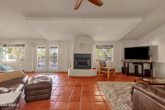 tiled living room featuring french doors, ceiling fan, and a large fireplace