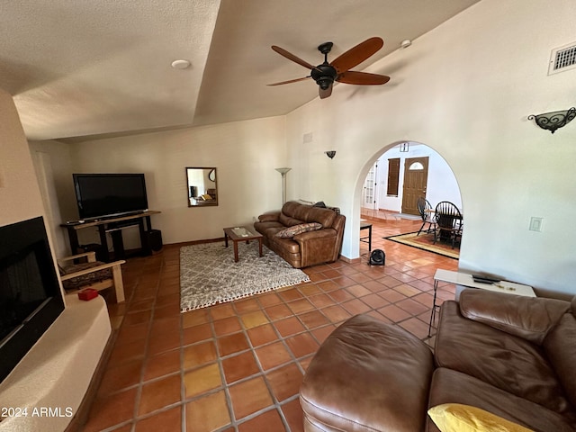 living room featuring a high ceiling, ceiling fan, a textured ceiling, and dark tile patterned flooring