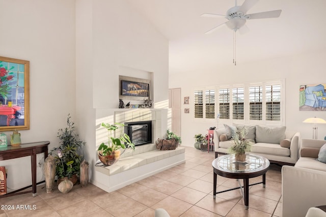 tiled living room featuring a tiled fireplace, ceiling fan, and high vaulted ceiling