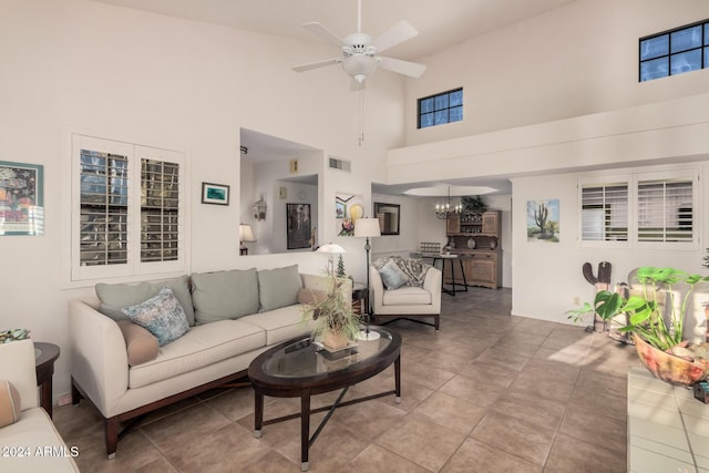 living room featuring ceiling fan with notable chandelier, a high ceiling, and light tile patterned flooring