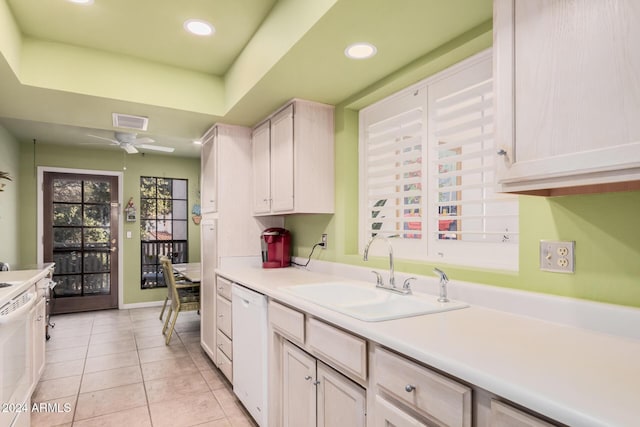 kitchen featuring white appliances, light tile patterned floors, ceiling fan, a tray ceiling, and sink