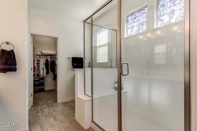 bathroom with plenty of natural light, a shower with shower door, and wood-type flooring