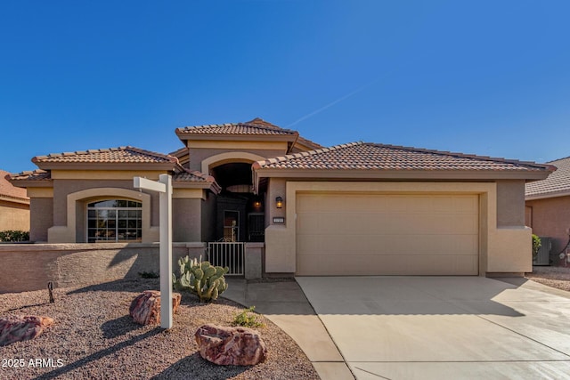 mediterranean / spanish house featuring a garage, driveway, a tiled roof, and stucco siding