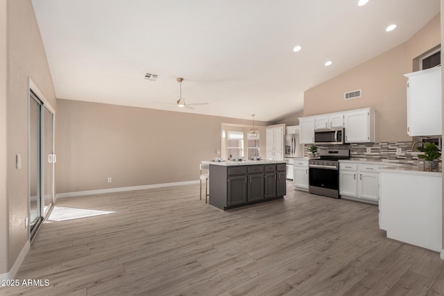 kitchen featuring appliances with stainless steel finishes, decorative light fixtures, a center island, light countertops, and white cabinetry