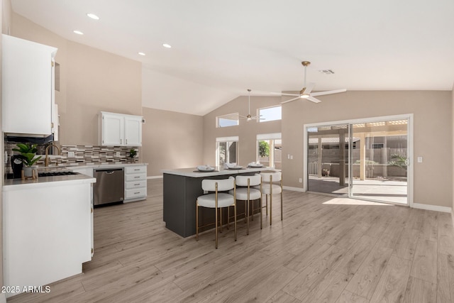 kitchen with white cabinetry, dishwasher, ceiling fan, tasteful backsplash, and a kitchen island