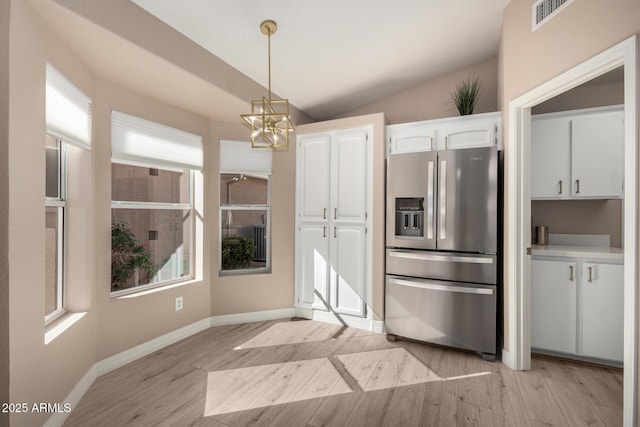 kitchen featuring lofted ceiling, white cabinetry, light wood-style floors, hanging light fixtures, and stainless steel fridge