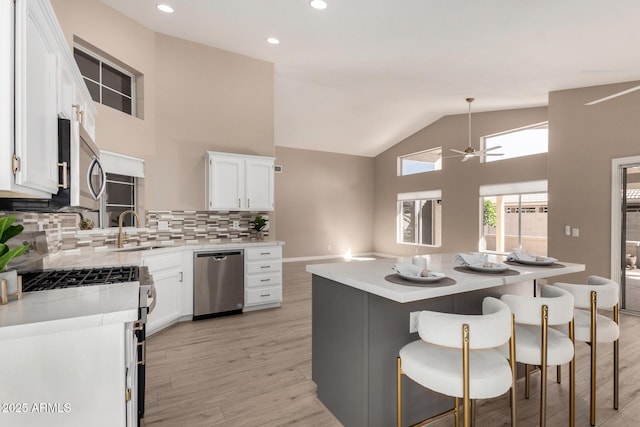 kitchen featuring white cabinets, a kitchen island, stainless steel appliances, and a sink