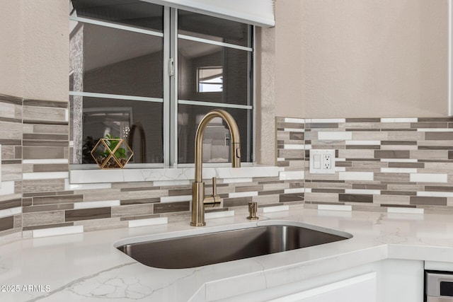 details with a textured wall, light countertops, a sink, and decorative backsplash