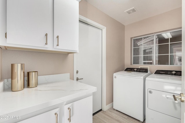 laundry room featuring cabinet space, washing machine and dryer, visible vents, and light wood finished floors