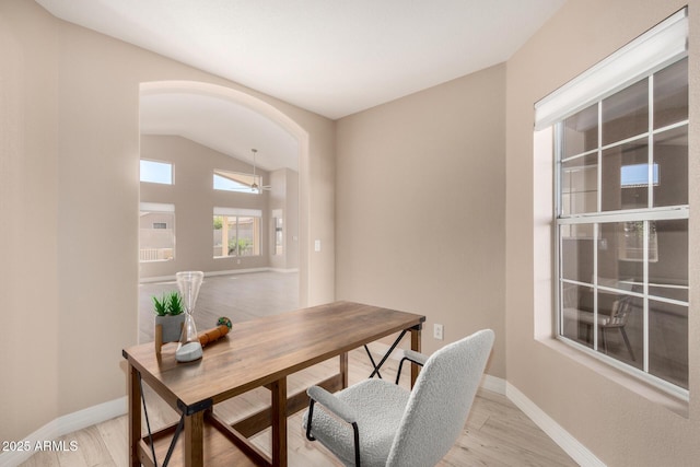 office with light wood finished floors, baseboards, and arched walkways