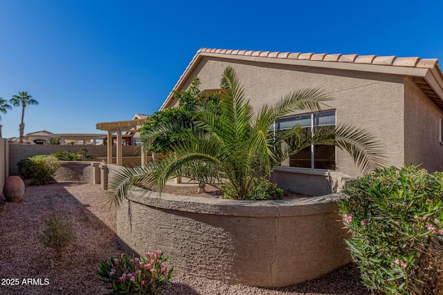 view of home's exterior with a pergola, fence, and stucco siding