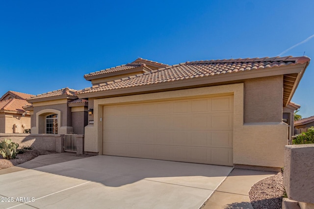 mediterranean / spanish home featuring concrete driveway, an attached garage, a tile roof, and stucco siding