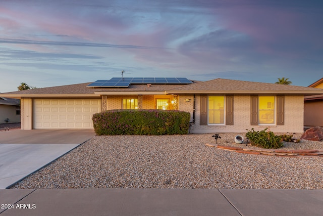 ranch-style home with a garage and solar panels