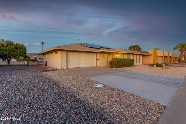 single story home with a garage and solar panels