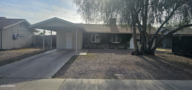 ranch-style home featuring fence, concrete driveway, an attached carport, and a chimney