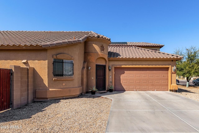 mediterranean / spanish-style home with stucco siding, fence, concrete driveway, an attached garage, and a tiled roof