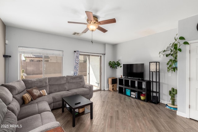 living area featuring visible vents, baseboards, wood finished floors, and a ceiling fan