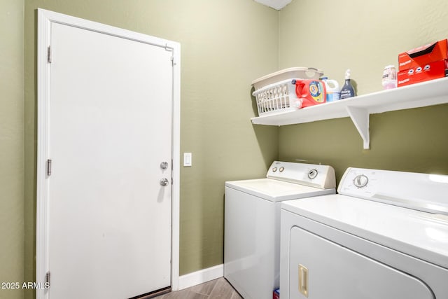 clothes washing area featuring laundry area, light wood-style flooring, washing machine and dryer, and baseboards