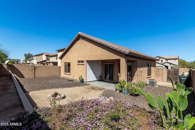 rear view of house with central air condition unit, stucco siding, a gate, a fenced backyard, and a patio area