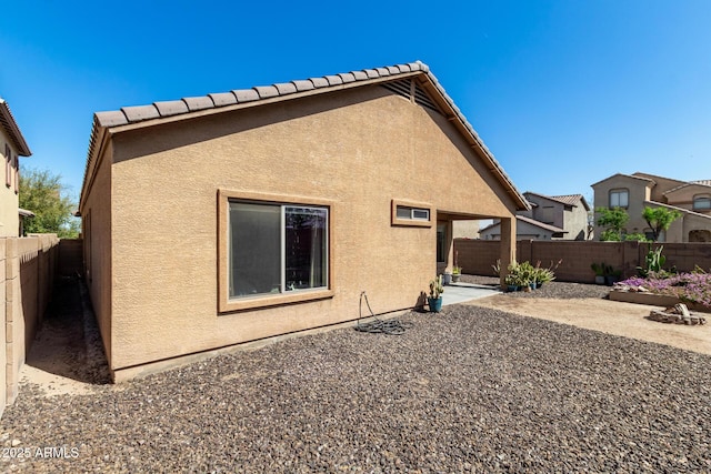 rear view of property with stucco siding, a fenced backyard, and a patio area