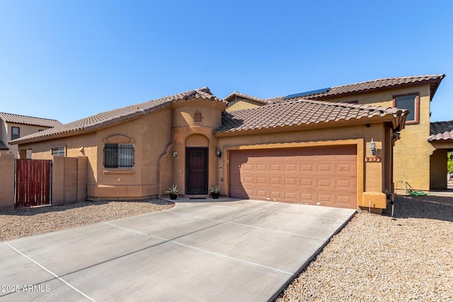 mediterranean / spanish house with concrete driveway, a tiled roof, an attached garage, and stucco siding