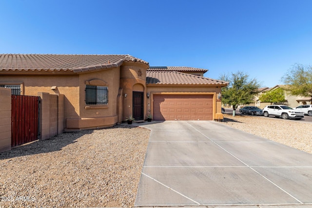 mediterranean / spanish home with fence, concrete driveway, a tile roof, stucco siding, and a garage