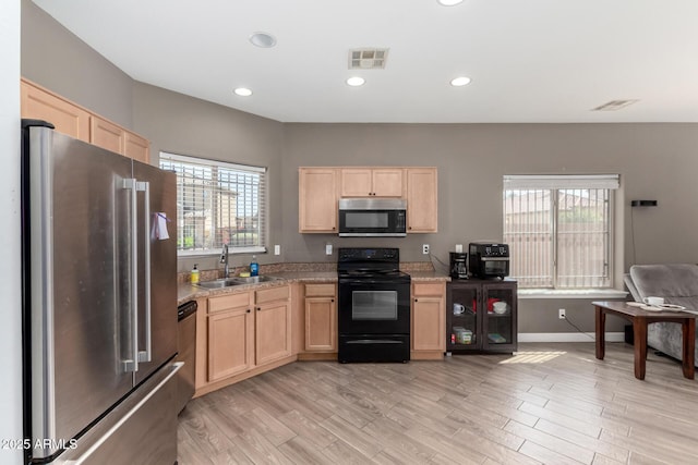 kitchen featuring light wood-type flooring, light brown cabinets, a sink, appliances with stainless steel finishes, and light countertops