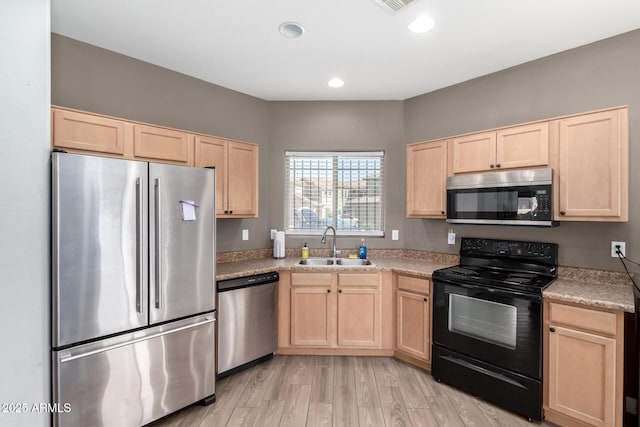 kitchen with light brown cabinetry, a sink, recessed lighting, light wood-style floors, and appliances with stainless steel finishes